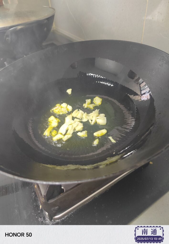 Add minced garlic and stir - fry for about 10–15 seconds until fragrant but not browned.